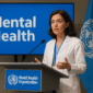 Suasana kampanye kesehatan mental global dengan tenaga medis WHO berbicara di depan audiens internasional di ruang konferensi modern tahun 2025.”